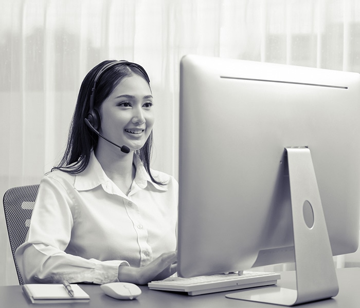 Asian call center with headset and microphone working on her laptop. Female operator provide exceptional customer service. Supportive call center agent helping customer on inquiry. Enthusiastic